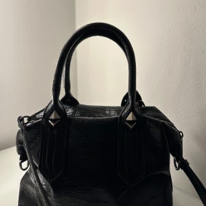 Handväska  - Säljer denna snygga handväska från Zara. Den är svart med nit detaljer, de går även att ta bort det justerbara axelbandet, om man föredrar det. Väskan är rymlig och bra. Endast använd fåtal gånger. 