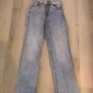 Blå jeansbyxor från H&M - Snygga blå jeansbyxor från H&M i storlek 36. De har en klassisk design med hög midja och raka ben. Perfekta för en avslappnad stil.