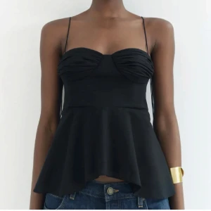 Svart ärmlös topp med volang - Snygg svart ärmlös topp med smala axelband och volangdetalj. Slutsåld topp! Med prislappen på!