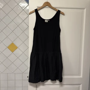 Svart klänning från Twist & Tango - Snygg svart klänning från Twist & Tango i storlek S. Den är ärmlös med en avslappnad passform och har en lätt rynkad kjoldel som ger en fin siluett. Perfekt för en stilren look.