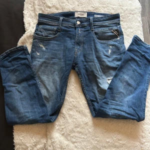 Replay jeans me slitningar  - Tja! Säljer ett par replay jeans i modellen anbass som sitter riktigt skönt,Skick 9/10, pris 600kr nypris 1500kr knappt använda där av ett sjukt bra pris! Strl 30/30