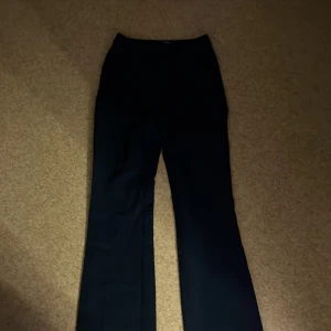 Svarta kostymbyxor från Bik Bok - Snygga svarta kostymbyxor från Bik Bok i storlek 34. Byxorna har en klassisk design med dragkedja och knapp framtill. Perfekta för en stilren look.