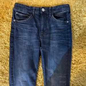 Mörkblå jeansbyxor - Snygga mörkblå jeansbyxor med klassisk femficksdesign och knappgylf. Perfekta för en avslappnad stil. De har en rak passform och är tillverkade i ett slitstarkt denimtyg.
