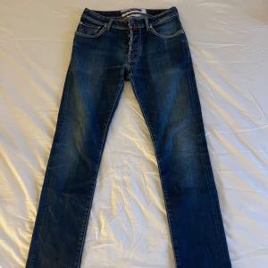Blå jeans från Jacob Cohen - Snygga blå jeans från Jacob Cohen med klassisk femficksdesign och en stilren look. De har en normal passform och är tillverkade i högkvalitativt denim. Perfekta för en avslappnad stil. Använda med försiktighet. QR kod för äkthetsintyg finns i byxorna, som visas på bilden. Nypris 6200kr