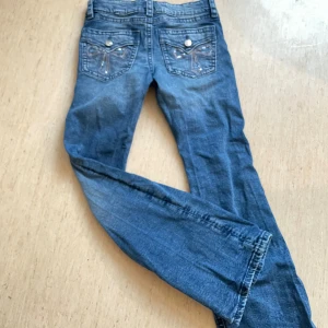 Blå jeans från Gina Tricot - Snygga blå jeans från Gina Tricot med dekorativa bakfickor och knappar🩷. Perfekta för en avslappnad stil.💕 De har en klassisk bootcut passform och dom är lågmidjade💕Säljer dessa för 150kr💕Hör av er vid intresse av bootcut jeansen från Gina tricot💕💕