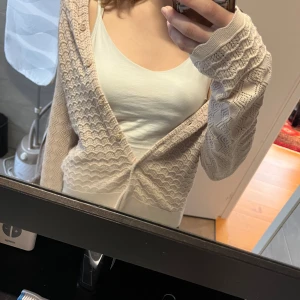 Beige stickad kofta från Odd Molly - Säljer en snygg beige stickad kofta från Odd Molly med ett fint hålmönster. Koftan har långa ärmar och knappar framtill. Perfekt för att lägga till en touch av stil till din outfit.