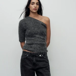 Grå oneshoulder topp - Snygg grå oneshoulder topp i fluffigt material. Perfekt för en trendig look med sin unika design och korta ärm. Passar bra till både jeans och kjol.