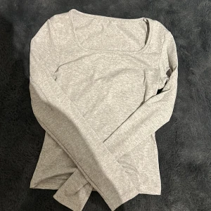 Grå långärmad topp - Säljer en stilren grå långärmad topp i mjukt material. Perfekt för lager-på-lager eller att bära som den är. Enkel och mångsidig design som passar till det mesta. Hör av dig vid intresse!