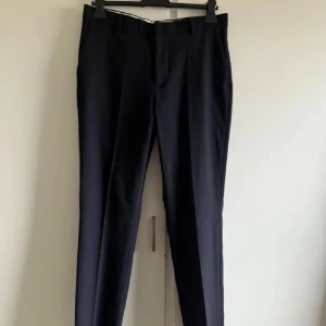  kostymbyxor - Mörkblåa svarta kostymbyxor från H&M. De har en klassisk design med raka ben och en midwaist passform. Perfekta för formella tillfällen eller en stilren vardagslook.