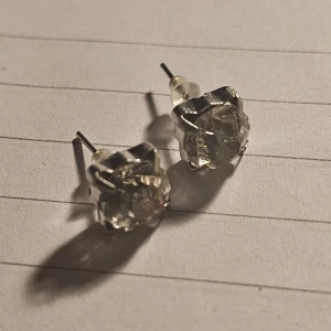 Silverfärgade örhängen med klar sten - Snygga silverfärgade örhängen med en klar, gnistrande sten i mitten. Perfekta för att ge en elegant touch till din look. Vet ej material, anledningen till det låga priset är för att jag rensar lager 🙂