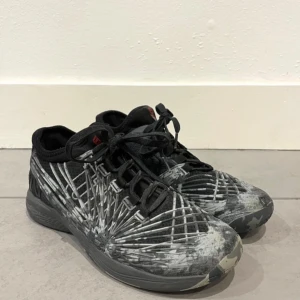 Svartgrå tennisskor från Wilson - Snygga tennisskor från Wilson i svart och grått med ett unikt mönster. Skorna har snörning och en slitstark sula perfekt för tennisbanan. Perfekta för dig som vill ha både stil och funktion på banan.