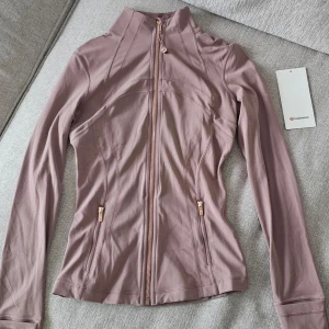 Lululemon Twilight Rose Gold Define Jacket - (Sänker priser till 1099kr. Läggs ut på Vinted på söndag!)☆LIMITED EDITION☆! Otroligt fin Lululemon Define Jacket i färgen Twilight Rose gold. Storlek 4. Motsvarar Small. ♡ ( Använd en gång. Foto nr ett är mitt. Dom andra är för se hur den sitter och ser ut. )