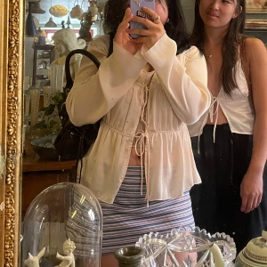 Beige satinblus från Zara - Säljer en elegant beige blus i satin från Ginatricot. Blusen har långa ärmar och knytning framtill som ger en fin detalj. Perfekt för en stilren look.