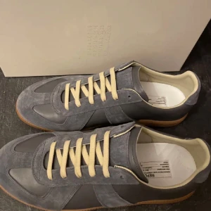 Maison Margiela Grå - Skorna har en stilren design med mockadetaljer och en bekväm passform. Perfekta för en avslappnad stil. Box och dustbag samt kvitto finns.