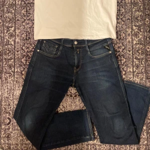 Mörkblå jeans från Replay - Snygga mörkblå jeans från Replay i modellen Anbass.   Snygg wash old lite snygga slitningar.Jeansen har en normal passform och är tillverkade i ett stretchigt material för extra komfort. Storlek 30W-32L