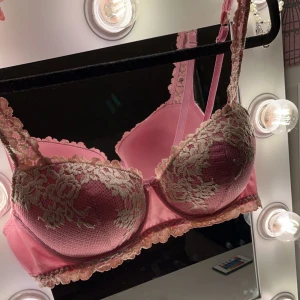 Rosa spets-bh - Säljer en söt rosa bh med vacker spetsdetalj i rosa. Bh:n har justerbara axelband och en mjuk vaddering för extra komfort. Perfekt för att känna sig både bekväm och elegant. Bh:n är ifrån Intimissimi!