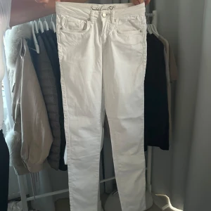 Vita jeans från Smashed Lemon - Snygga vita jeans från Smashed Lemon med en hjärtformad knappdetalj. De har en klassisk femficksdesign och är perfekta för en stilren look. Passar bra till både vardag och fest. Nypris är 1300kr