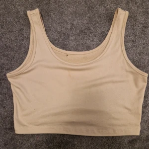 Beige  linnetopp - Säljer en stilren beige  linnetopp. Perfekt för varma dagar med sitt mjuka material. 