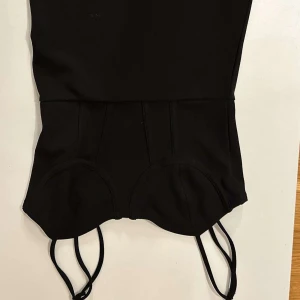 Svart baddräkt från H&M - Snygg svart kort fest klänning från hm. den är avklippt i botten och är kort. super snygg corset liknande topp och sitter tight 