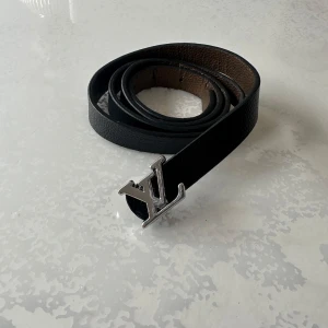 Svart bälte med silverfärgat spänne - Snyggt svart bälte i skinn med ett stilrent silverfärgat spänne. Perfekt för att ge din outfit en lyxig touch. Passar till både jeans och klänning.