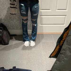 Blå jeans från Hollister - Snygga blå jeans från Hollister med slitna detaljer och bootcut. Stretchiga! Innerbenslängd 82 och midjemåttet är 32. Lite för korta för mig som är 175!