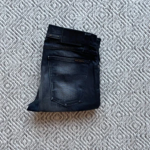 Nudie jeans - Säljer ett par riktigt snygga svarta Nudie jeans i modell Tube Tom. Jeansen har en väldigt unik och speciell tvätt som kallas för Rough Raven. Jeansen är helt nya men har inga lappar kvar. Det är storlek W31/L34. Vid minsta fråga eller fundering är det bara att höra av sig👍😁