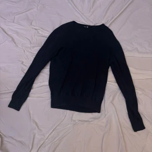 Mörkblå tröja från Basic - Säljer en stilren mörkblå tröja från Basic. Tröjan har en enkel design med långa ärmar och rund halsringning. Perfekt för våren och sommaren. 