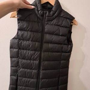 Svart väst från Grekland - Säljer en stilren svart väst från M&S Collection. Västen har en dragkedja framtill och är perfekt för lager-på-lager under kyligare dagar. Den är lätt och bekväm att bära.