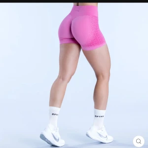 Rosa träningstights från DFYNE - Säljer ett par snygga rosa träningstights från DFYNE. De är hög/medium midjade och har en tight passform som framhäver formerna. Perfekta för gymmet eller löprundan! Materialet är stretchigt och bekvämt, vilket gör dem idealiska för intensiv träning. 🩷