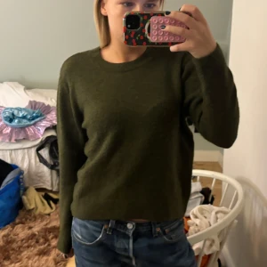 Olivgrön stickad tröja  - Säljer en mysig olivgrön stickad tröja i bra skick. Tröjan är lite kortare vilket jag tycker e jätte najs till jeans✨✨ skulle säga att andra bilden är mest rättvis för hur färgen ser ut!