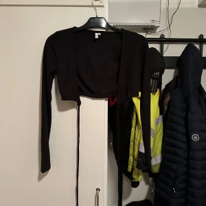 Svart bolerotopp från Nelly - Säljer en snygg svart bolerotopp från Nellyi storlek S. Perfekt för att lägga till en extra touch till din outfit. Den är långärmad och har en tight passform som framhäver figuren. Passar bra till både vardag och fest!