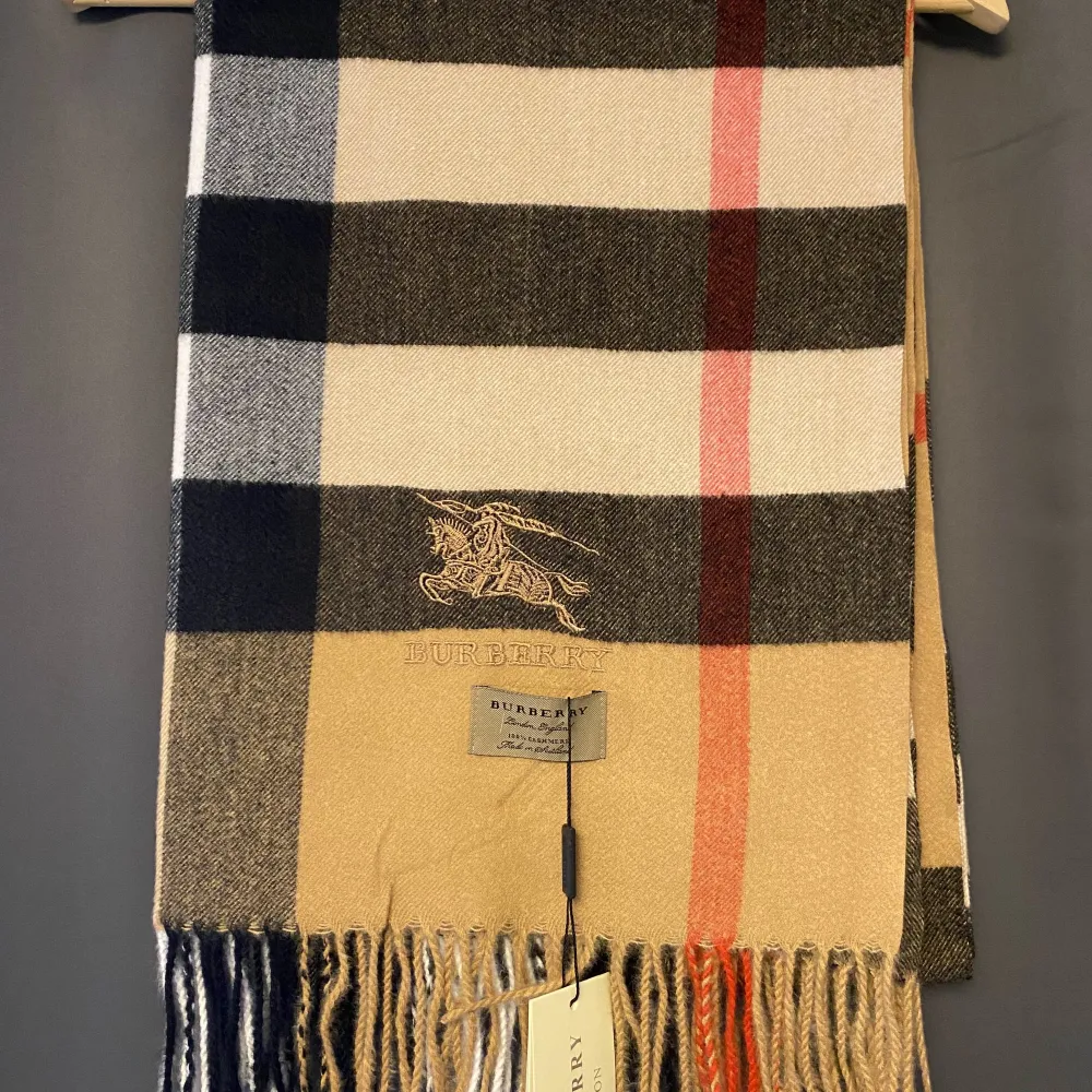 Säljer en superfin rutig halsduk från Burberry i klassiska färger som beige, svart och röd. Och har fransar i ändarna. Perfekt för vintern och kommer med originalförpackning. Ett måste för den stilmedvetna! 🧣✨. Övrigt.