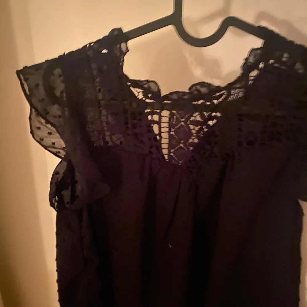 Säljer en elegant svart blus med vackra spetsdetaljer vid halsen och ärmarna. Perfekt för både fest och vardag. Blusen har en lös passform och är tillverkad i ett lätt och luftigt material. Ett måste i garderoben för den som älskar stilrena plagg!. Yläosat.