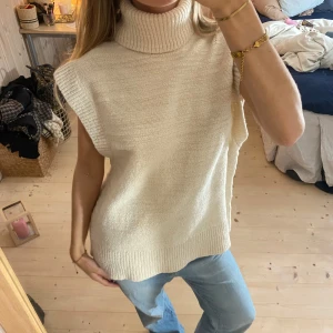 Beige stickad ärmlös polotröja - Säljer en superfin beige stickad polotröja utan ärmar. Den har en mysig polokrage och är i ett mjukt material som känns skönt mot huden. I jätte bra kvalitet från COS💕