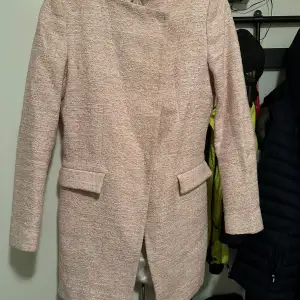 Säljer en elegant beige kappa från Zara Basic Collection i storlek M. Den har en stilren design med långa ärmar och diskreta fickdetaljer. Perfekt för höst och vår! Kappan är i mycket bra skick och har en mjuk, bekväm passform. Passar både till vardags och festliga tillfällen.