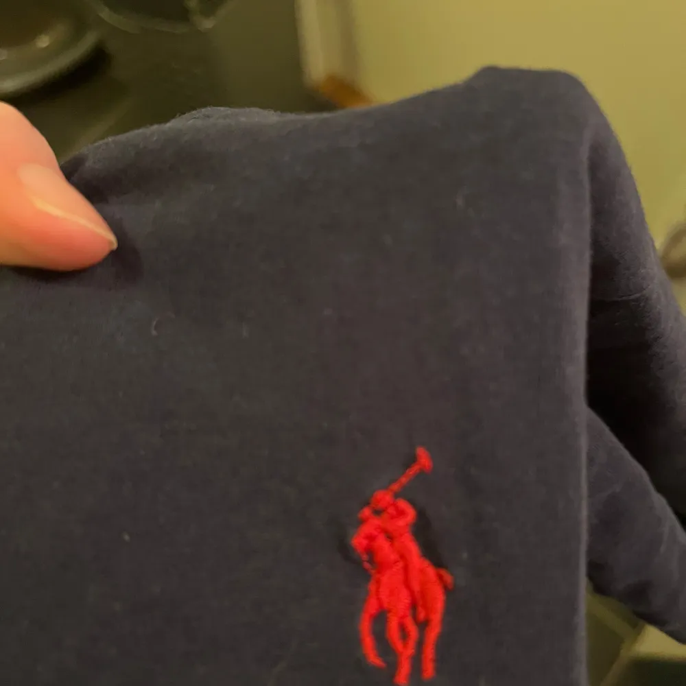 Säljer en klassisk svart t-shirt från Polo Ralph Lauren i storlek M. Den har en röd broderad logga på bröstet och är i mycket bra skick. Perfekt för en stilren och avslappnad look!. T-shirts.