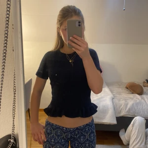 Mörkblå topp från Gina Tricot - Säljer en söt mörkblå topp från Gina Tricot i storlek 146/152. Toppen har korta ärmar och en volangdetalj vid nederkanten som ger en fin touch. Perfekt för både vardag och festliga tillfällen. Materialet är stretchigt och bekvämt. Passar bra till jeans eller kjol!