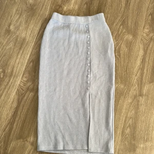 ribbad kjol med knappar - Säljer en superfin ribbad långkjol med knappar framtill. Kjolen har en stilren design och en liten slits som ger extra rörelsefrihet. Har även en matchande tröja 