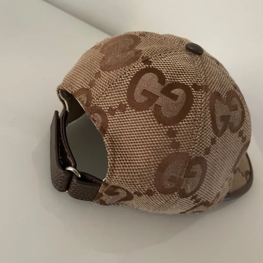 Säljer en snygg beige keps från Gucci med det klassiska GG-mönstret i brunt. Kepsen har en stilren design med en böjd skärm och är perfekt för både vardag och fest. Den är i mycket bra skick och har en bekväm passform. Perfekt accessoar för att lyfta din outfit!. Asusteet.
