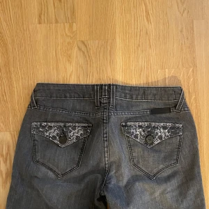 Lågmidjade jeans med utsmyckade fickor - Lågmidjade gråa jeans med utsmyckade fickor! Knappt använda då de inte passar mig perfekt 