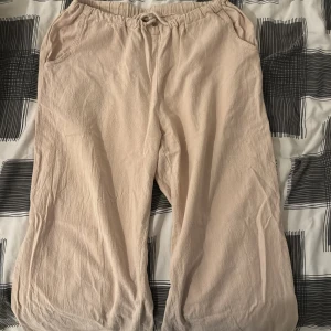 Beige linnebyxor - Säljer ett par bekväma beige linnebyxor med elastisk midja och avslappnad passform. Perfekta för varma sommardagar eller en avslappnad dag hemma. Byxorna har en loose fit och är gjorda i ett lätt och luftigt material. Passar perfekt för en chill stil!