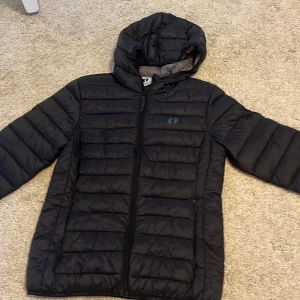 Svart pufferjacka från Hangten - Säljer en svart pufferjacka från Hangten i storlek XS. Jackan har en mysig huva och dragkedja framtill. Perfekt för kalla dagar med sin quiltade design som håller värmen. Den är i mycket bra skick och redo för nya äventyr! 🖤