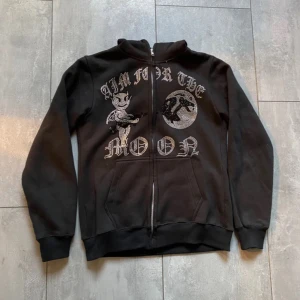 Aim for the moon zip! - Säljer en svart hoodie med coolt tryck 'Aim for the Moon' och en figur på framsidan. Den har dragkedja och långa ärmar, perfekt för en avslappnad stil. Passar bra till både vardag och chillkvällar. 🖤