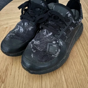 Svarta Adidas sneakers med Gore-Tex - Säljer ett par svarta Adidas sneakers i storlek 39. De har ett coolt mönster och är utrustade med Gore-Tex för att hålla fötterna torra. Skorna har en robust sula från Continental för extra grepp. Perfekta för höst och vår!