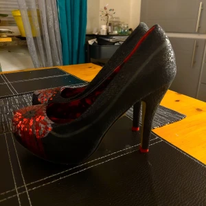 Iron Fist, High heal, Högklackat, Rockabilly.  - Skitsnygga höga Pumps från Iron Fist. Läckert svarta med röda paljetter på grå botten, klackhöjd 12 cm. Jag har dansat i dessa inomhus, så på undersidan är det nåt litet märke men inget som skymmer, I övrigt superfint skick. Strl 38. 