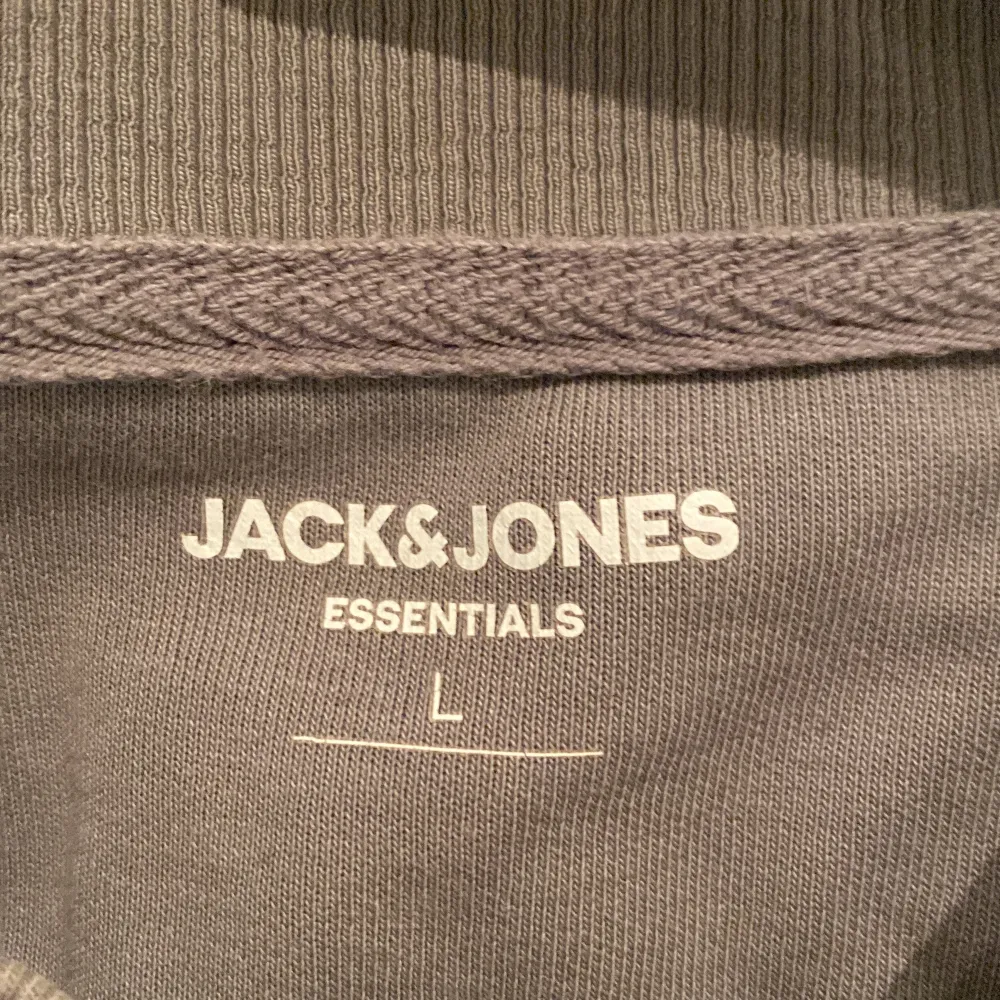 Säljer en stilren grågrön sweatshirt i bomull från Jack & Jones Essentials i storlek L. Tröjan har en klassisk rund hals och långa ärmar. Passar bra till jeans eller chinos för en avslappnad look.. Tröjor & Koftor.