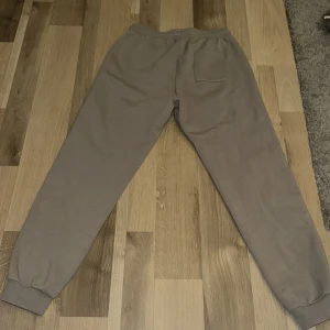Grå mjukisbyxor från Björn Borg - Säljer ett par grå mjukisbyxor från Björn Borg i storlek 170, passar 170-180. De är bekväma med elastisk midja och snörning för perfekt passform. Perfekta för en chill dag hemma eller en promenad i parken. Byxorna har en bakficka och muddar vid bensluten för extra komfort. Org pris 500 Kr. 