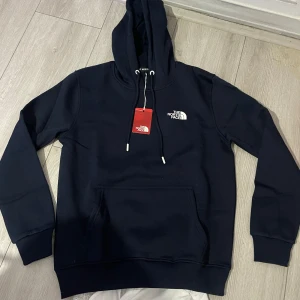 Nattblå hoodie - The North Face - Säljer en hoodie från The North Face i storlek M. Den är i nytt skick med etikett kvar. Helt oanvänd. (Den är från men avdelning, men funkar som unisex också). Nypris 948kr. Säljer för endast 499kr.