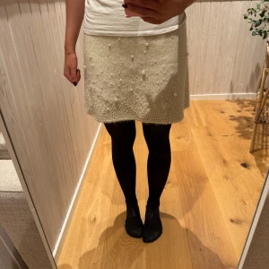 Vit kjol med pärlor från Zara - Snygg vit kjol från Zara dekorerad med pärlor. Kjolen har en kort längd. Tillverkad i ett mjukt material som ger en bekväm passform. Använd endast en gång💗