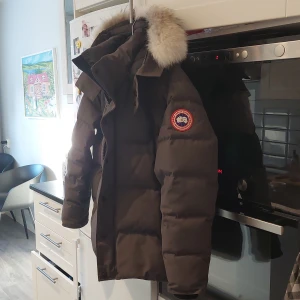 Canada Goose wyndham - Säljer en grå dunjacka från Canada Goose med pälsdetaljer på huvan. Jackan har en klassisk design med lång ärm och är perfekt för kalla vinterdagar. Den har en praktisk dragkedja och är tillverkad i slitstarkt material.äkta självklart ny pris ca 17k..storlek large skick 8 av 10 inga hål förutom en inne i fickan.fim fräsch väldigt lite använd ..säljes eller ev bytes..